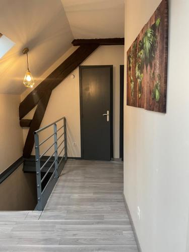 un couloir avec une porte noire et une peinture sur le mur dans l'établissement charmes de Lourdes 1, à Lourdes