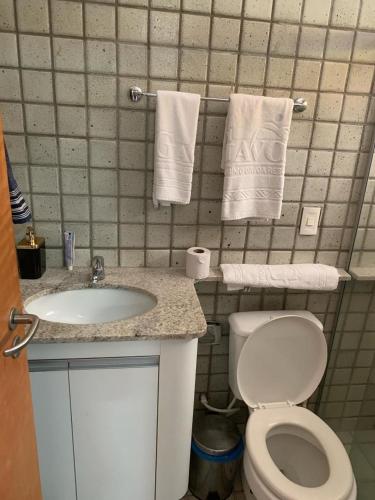 a bathroom with a toilet and a sink and towels at Gavoa Resort Flat 108 E in Igarassu