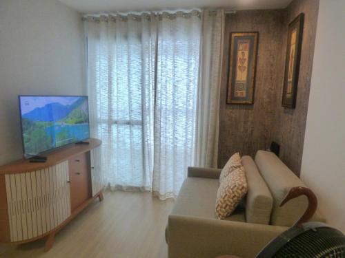 a living room with a couch and a flat screen tv at nityloft com piscina e academia em Icaraí in Niterói