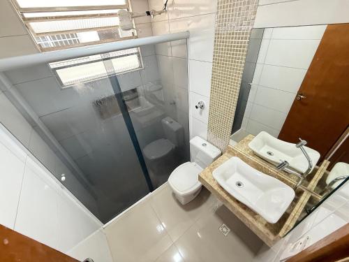 Un baño blanco con lavabo e inodoro. en Pies en la arena Playa Boqueirão II, en Praia Grande