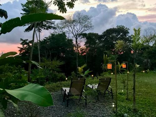 three chairs and a table in a field with trees at Yogachal Vista Mar Bamboo House in the Jungle in Ojochal