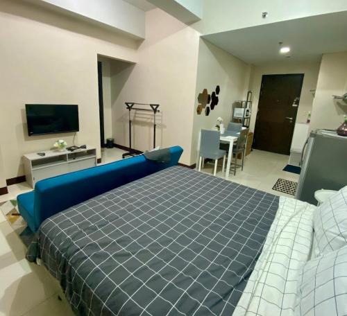 une chambre avec un lit bleu et un salon dans l'établissement studio flat at 101 Newport Boulevard, à Manille