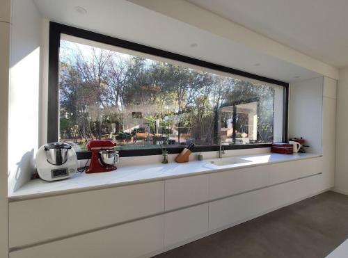 une cuisine avec une grande fenêtre au-dessus d'un évier dans l'établissement Villa avec piscine au milieu des bois, à Roquefort-les-Pins