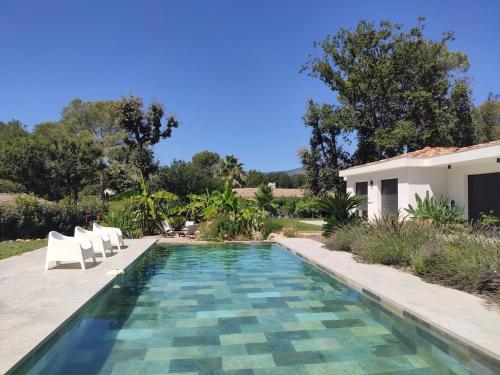 une piscine avec des chaises et une maison dans l'établissement Villa avec piscine au milieu des bois, à Roquefort-les-Pins