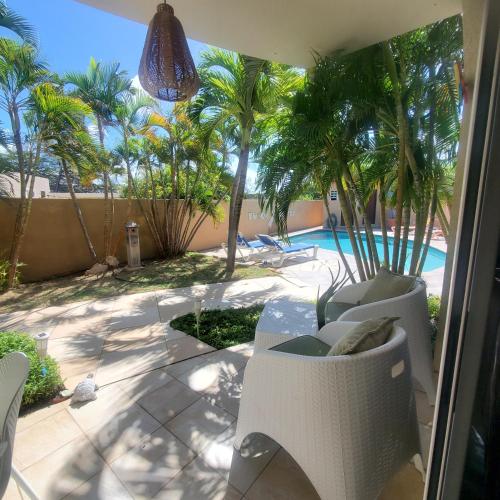 a view of a patio with palm trees and a pool at Bohemian Townhouse Palm Beach Aruba in Palm-Eagle Beach