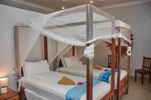 a bedroom with two beds with white drapes at Paje Beach Apartments & Hotel in Paje