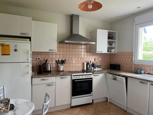 une cuisine avec des appareils blancs, une table et une fenêtre dans l'établissement Maison agréable et lumineuse, jardin vue nature, Nant Aveyron, à Nant