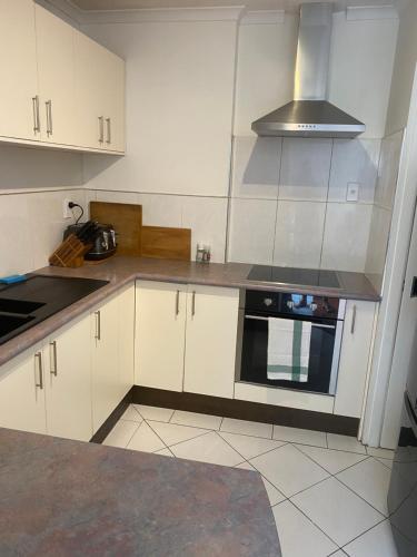 a kitchen with white cabinets and a stove top oven at Guesthouse in Half Moon Bay in Auckland