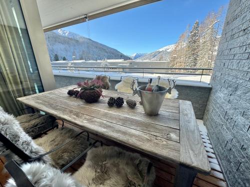 a wooden table sitting on a balcony with a window at Alpine Luxury Apartment Davos with Spa Access to 5 Star Hotel in Davos