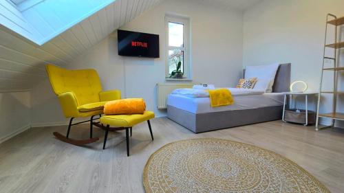 a bedroom with a bed and a chair and a tv at HAPPY HOMES YELLOW - Up to 8 - Küche - W-LAN - Netflix - Honig - Badewanne in Nidda