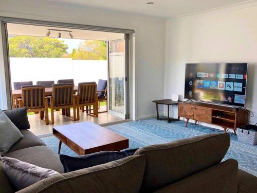 a living room with a couch and a flat screen tv at Family Getaway With LARGE Parent Retreat! in Shellharbour