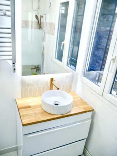 une salle de bain avec un lavabo et deux fenêtres dans l'établissement L'aurore de Clamart, à Clamart