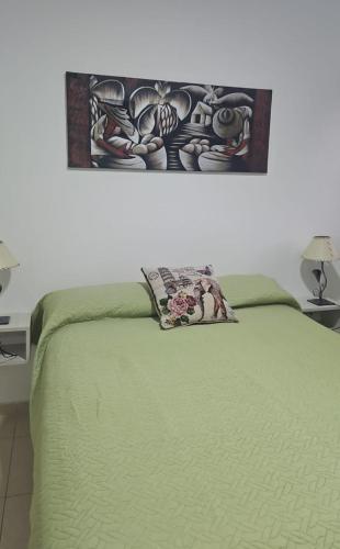 a bedroom with a green bed with a painting on the wall at Luma in Bahía Blanca