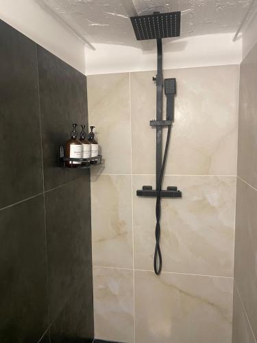 une douche avec pommeau de douche dans une salle de bain dans l'établissement Le Cocon - proche gare avec jardinet - 2 adultes et 1 bébé, à Bois-le-Roi