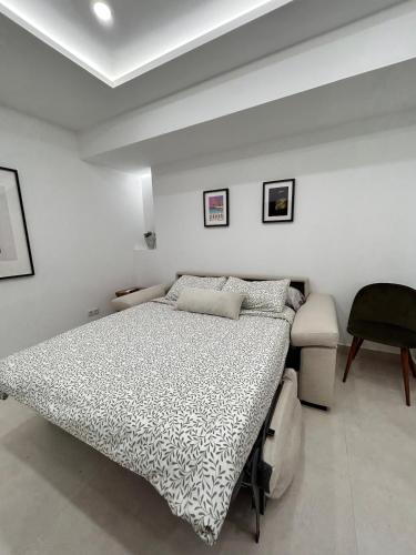 Un dormitorio blanco con una cama y una silla. en AeroSuites102 Alojamiento Madrid, en Madrid