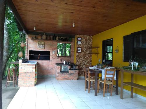 a kitchen with a brick fireplace and a table and chairs at Sítio em Nova Veneza - Caminho dos Pinheiros in Siderópolis