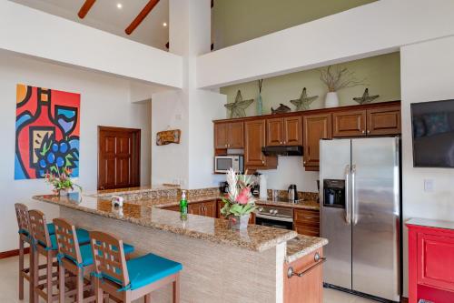 a kitchen with a large counter with chairs and a refrigerator at Sunset 303 - Ocean View 3 Br Condo in Tempate