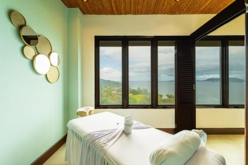 a bedroom with a bed and large windows at 360 Splendor 101B Ocean View Studio With Breakfast in Playa Flamingo