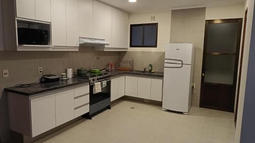 una cucina con mobili bianchi e un frigorifero bianco e nero di Alojamiento JPV a Sucre