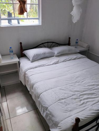 a bed with white sheets and pillows next to a window at Country Vibe 2 bedroom apartment in Vieux Fort