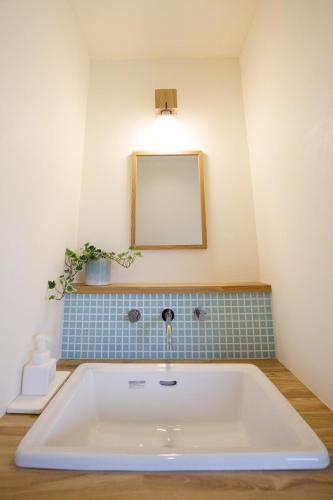 a bath tub with a sink and a mirror at SORADOMARI in Iizuka