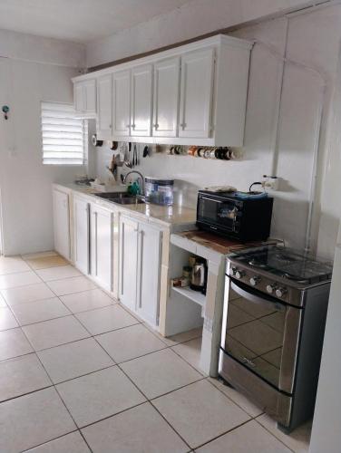 a kitchen with white cabinets and a stove top oven at Country Vibe 2 bedroom apartment in Vieux Fort