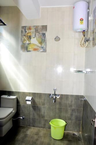 a bathroom with a toilet and a green bucket at Vanam Holidays in Ooty