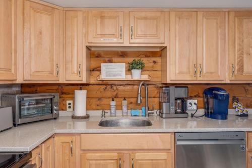 a kitchen with wooden cabinets and a sink and a microwave at Retrievers Retreat High Tech Log Cabin Oasis in Berkeley Springs