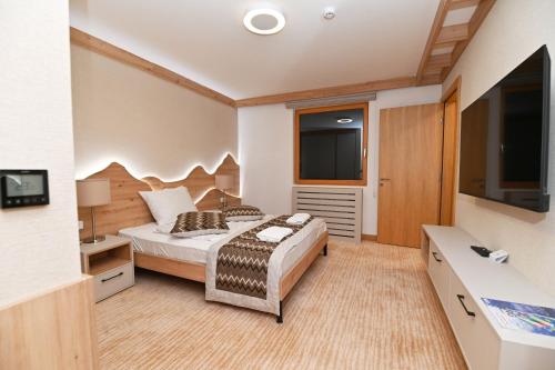 a bedroom with a bed and a flat screen tv at Apartman D343 Aparthotel Vucko Jahorina privat apartman in Jahorina
