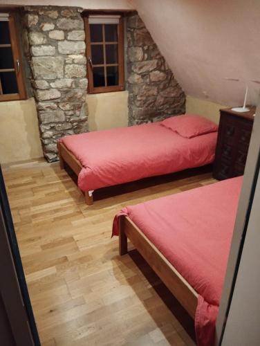 une chambre avec deux lits et un mur en pierre dans l'établissement Maison du manoir, à Kerlouan