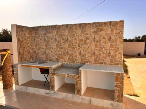 a stone wall with a bench against a brick wall at Villa raif in Djerba