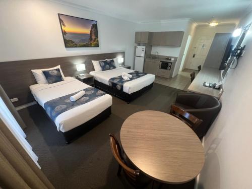 a hotel room with two beds and a table at Adelong Motel in Narrabri