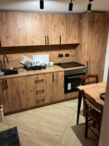 a kitchen with wooden cabinets and a stove and a table at Korja Apartments Mavrovo in Mavrovo