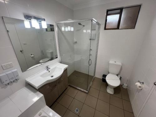 a bathroom with a shower and a toilet and a sink at Adelong Motel in Narrabri