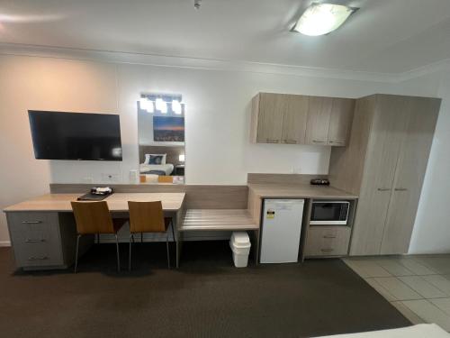 a kitchen with a table with chairs and a counter top at Adelong Motel in Narrabri
