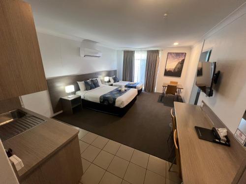 a hotel room with a king sized bed and a kitchen at Adelong Motel in Narrabri