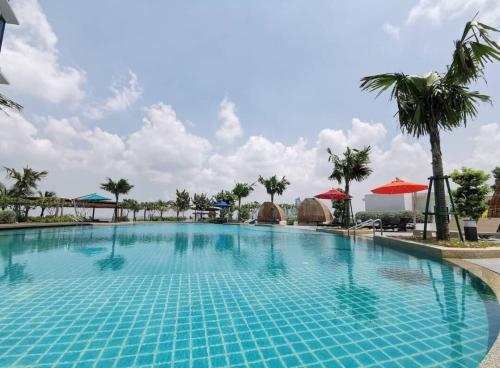 une grande piscine bleue avec des palmiers et des parasols dans l'établissement Almas Couple Cozy Premium Loft Netflix BySTAY, à Iskandar Puteri