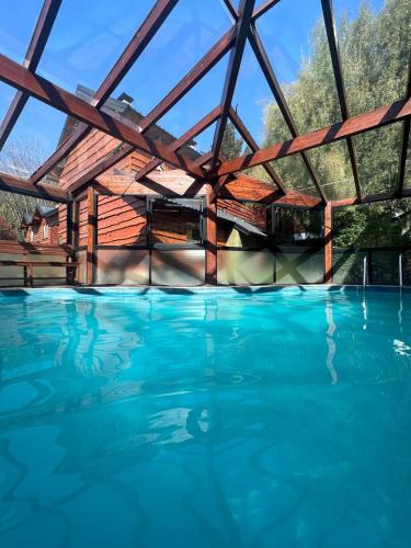 a large swimming pool with a wooden building at Cabañas Arique in San Martín de los Andes