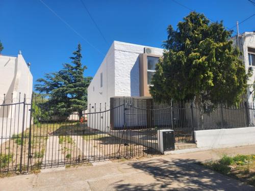 una cerca frente a una casa con un árbol en Beautiful Casa Madrynense, en Puerto Madryn