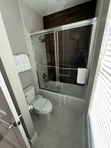 a bathroom with a toilet and a glass shower at Disney here we go in Orlando