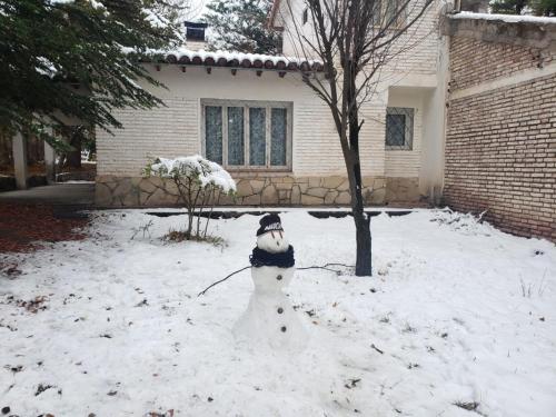 a snowman sitting in the snow in front of a house at La Clavelina in Potrerillos