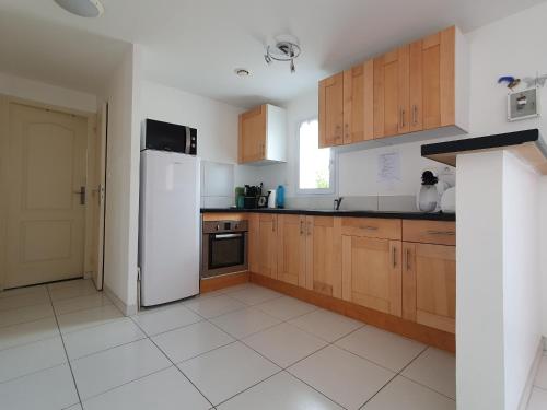 une cuisine avec des armoires en bois et un réfrigérateur blanc dans l'établissement Villa moderne 6 pers. proche plage, jardin, barbecue - FR-1-476-36, à La Faute-sur-Mer