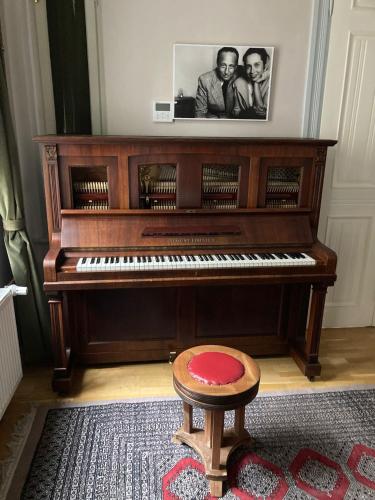 a piano with a stool and a picture of two men at Chopin Boutique in Warsaw