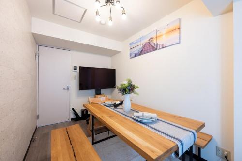 a living room with a wooden table and a television at 新宿駅まで12分渋谷駅まで22分最大8名様宿泊可能4ベッドルーム in Ogikubo