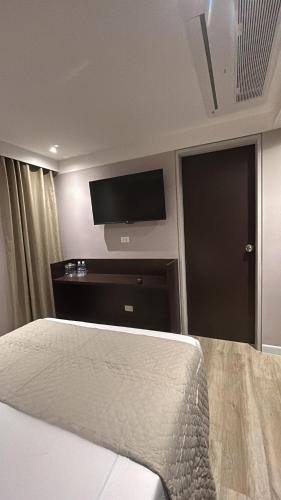 a bedroom with a bed and a flat screen tv at Hotel Grand Galaxie in Caracas