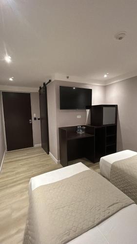 a hotel room with two beds and a desk at Hotel Grand Galaxie in Caracas