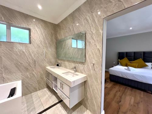 a bathroom with a sink and a bed and a mirror at Vinorisa Spa & Lodge in Pretoria