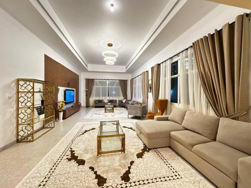a living room with a couch and a tv at Oasis Villa Stay by Lunar in Abu Dhabi