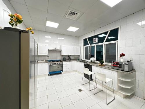 a large kitchen with white tile floors and white cabinets at Oasis Villa Stay by Lunar in Abu Dhabi