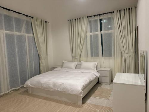 Un dormitorio blanco con una cama y dos ventanas. en Oasis Villa Stay by Lunar, en Abu Dabi